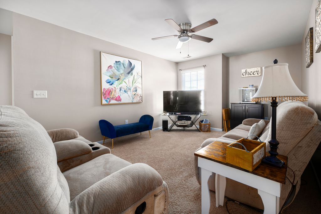 Beige reclining chairs arranged around a television in a spacious living room.