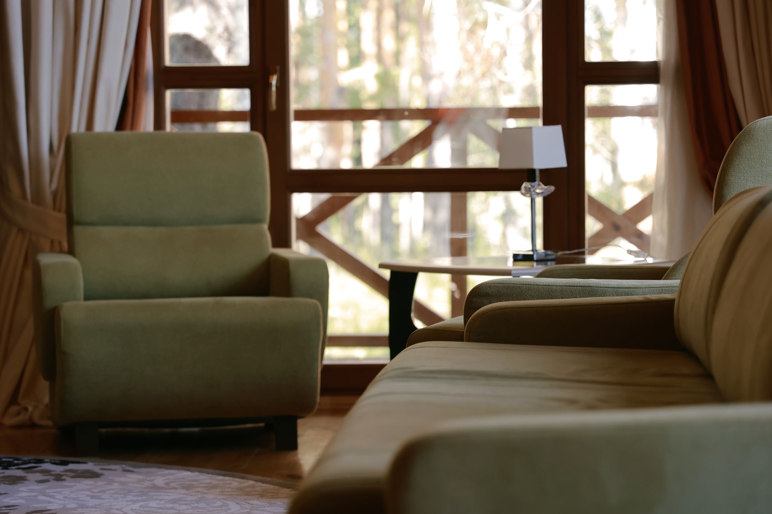 High-back upholstered armchairs beside a window in a warm living room.