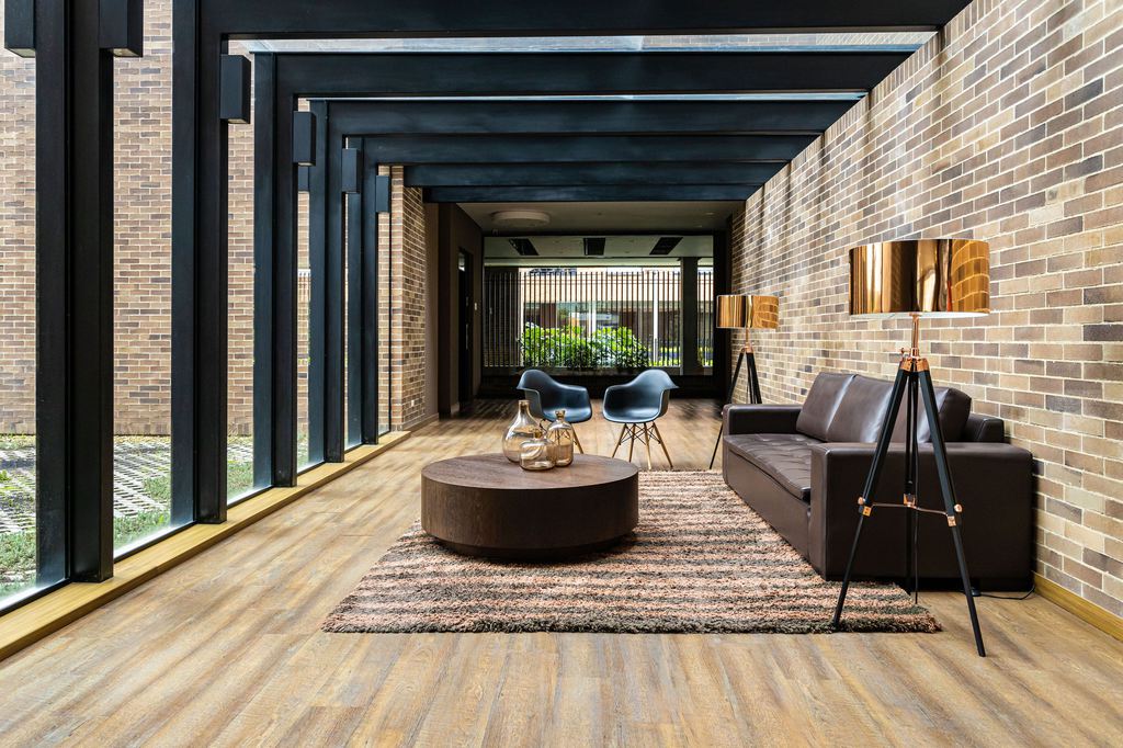 Large dark wood drum coffee table on an area rug beside a brown leather sofa in a modern living room.