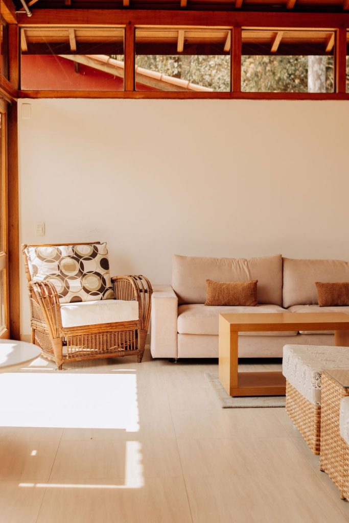 Beige sofa, wicker chair, and wooden coffee table arranged on light hardwood flooring in a bright living room.