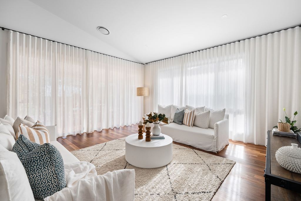 White fluted drum coffee table centered between two white sofas in a bright living room.