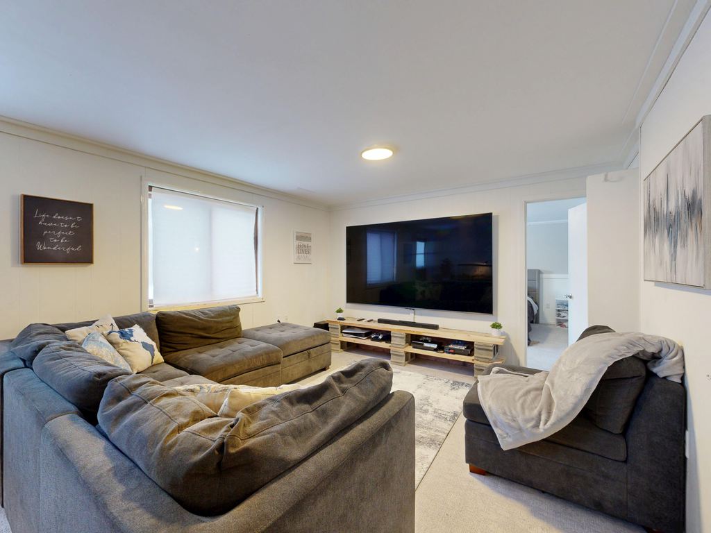 Gray L-shaped sectional sofa facing a wall-mounted TV with a clear central walkway and an accent chair.