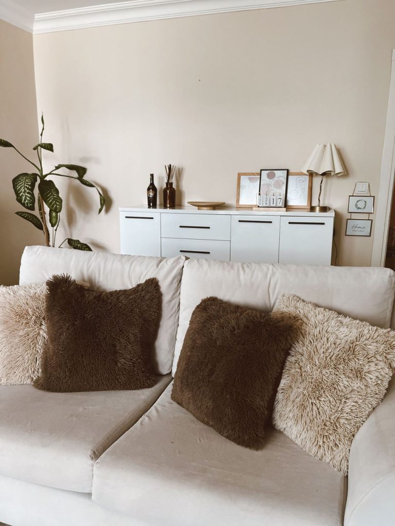 Light beige sofa with brown and cream textured pillows in a cozy neutral living room.