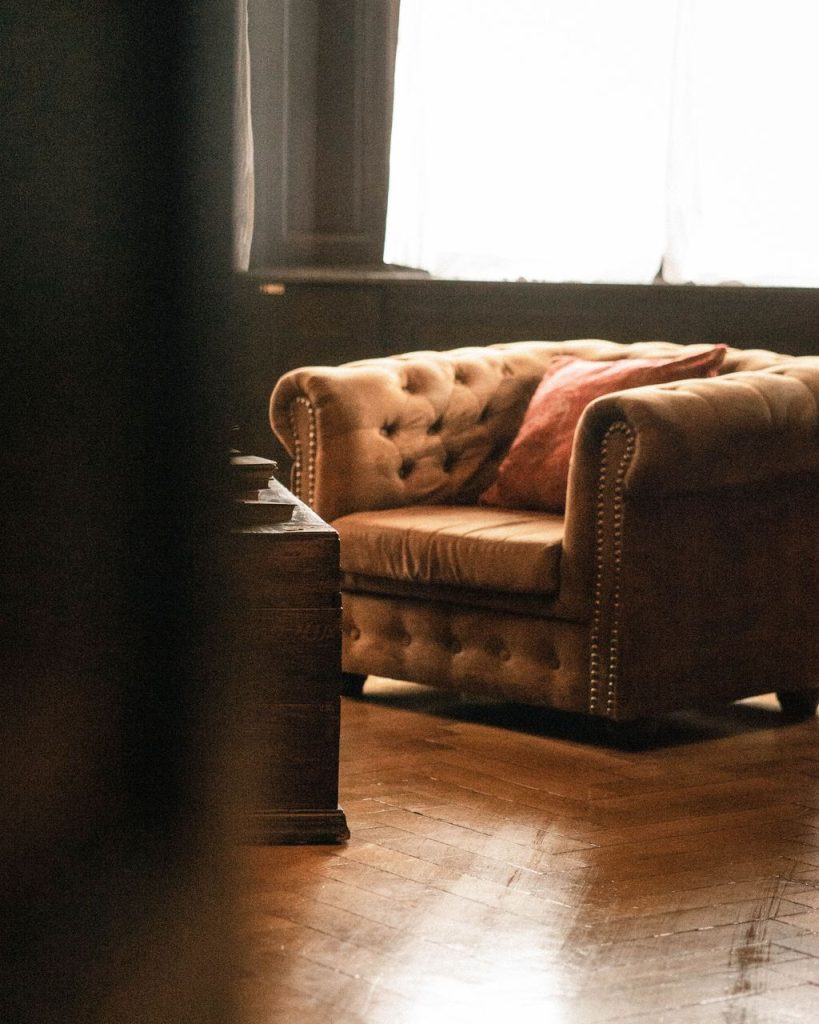 Tufted leather sofa and dark wood furniture arranged on polished hardwood flooring.