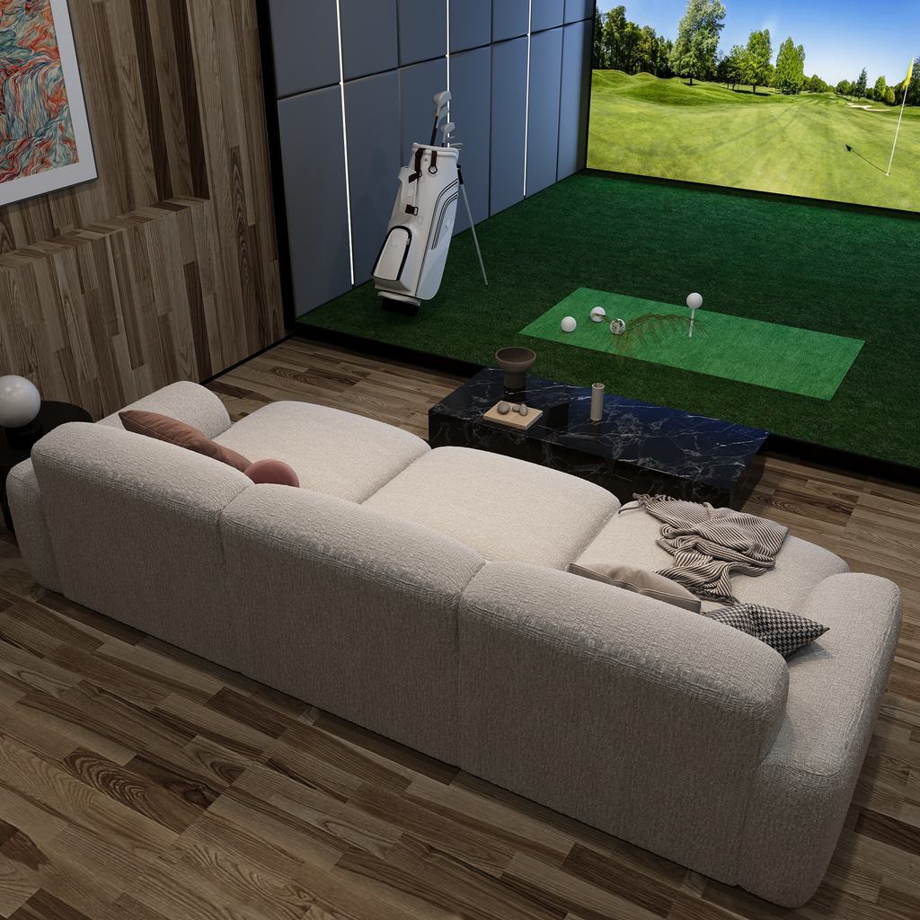 Cream power sofa bed extended for lounging in a modern indoor golf simulator room.