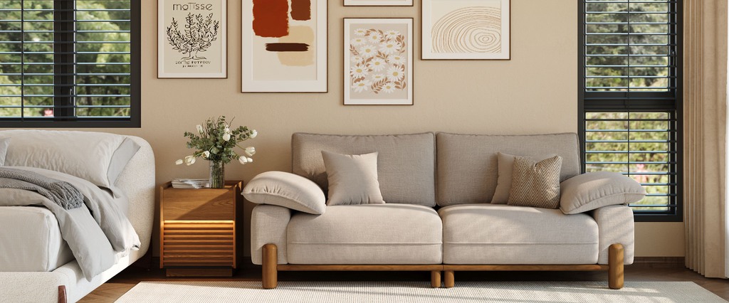 Cream low-arm sofa with oversized arm cushions and a wood base in a warm bedroom sitting area.