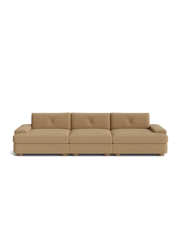 Beige three-seat sofa with very low padded arms, tufted back cushions, and a low-profile frame.