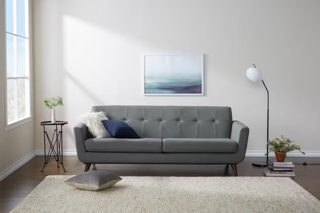 Gray upholstered sofa beside a floor lamp and side table in a bright modern living room.