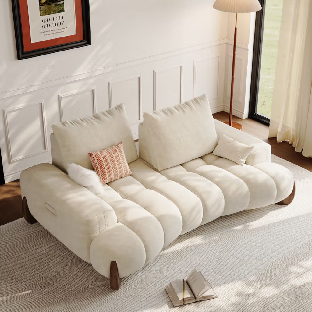 Cream deep-seat sofa with oversized cushions in a sunlit reading corner, with an open book on the rug.