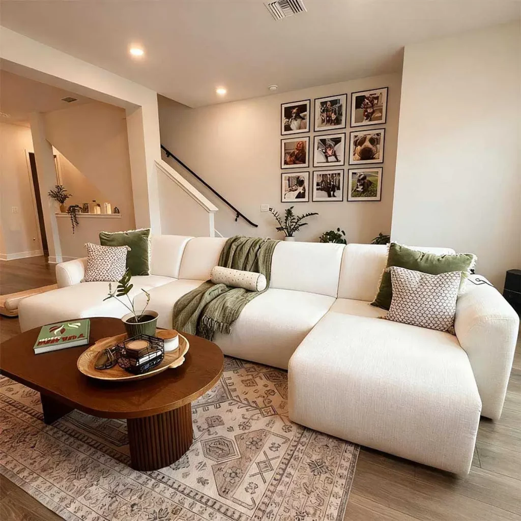White sofa bed in a bright living room with a coffee table, rug, pillows, and wall art.