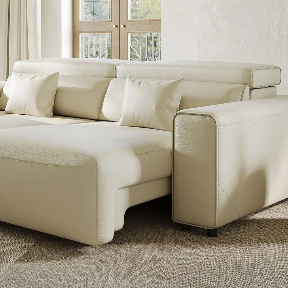 Cream sleeper sofa with wide chaise and padded armrest in a bright living room.