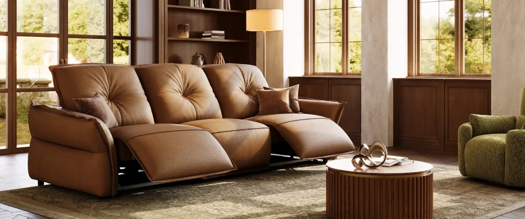 Brown leather reclining sofa with extended footrests in a warm, sunlit living room.