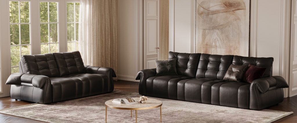 Black leather reclining sofa set in a bright elegant living room with large windows and a round coffee table