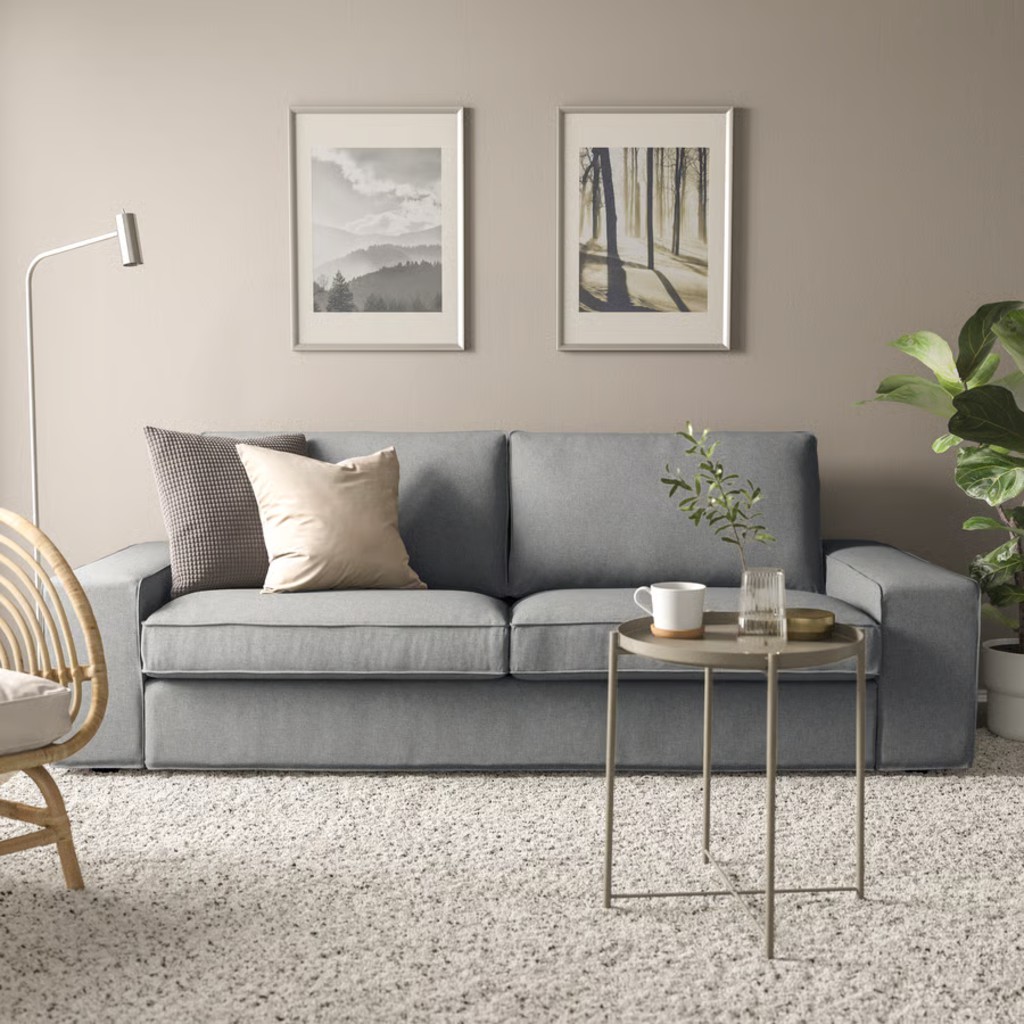 Gray low-arm sofa with broad square arms, two seat cushions, and throw pillows in a modern living room.