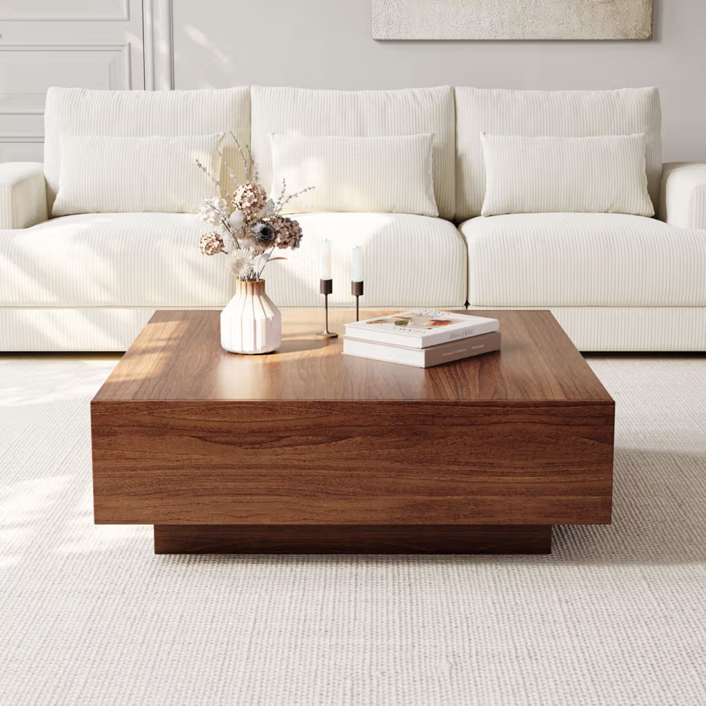 Large square walnut coffee table in front of a cream sofa in a bright modern living room.