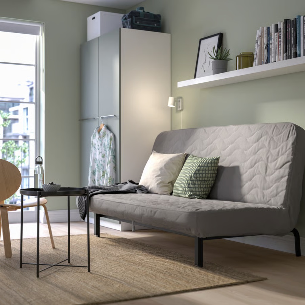 Gray sofa bed with cushions in a compact multipurpose room with built-in storage.