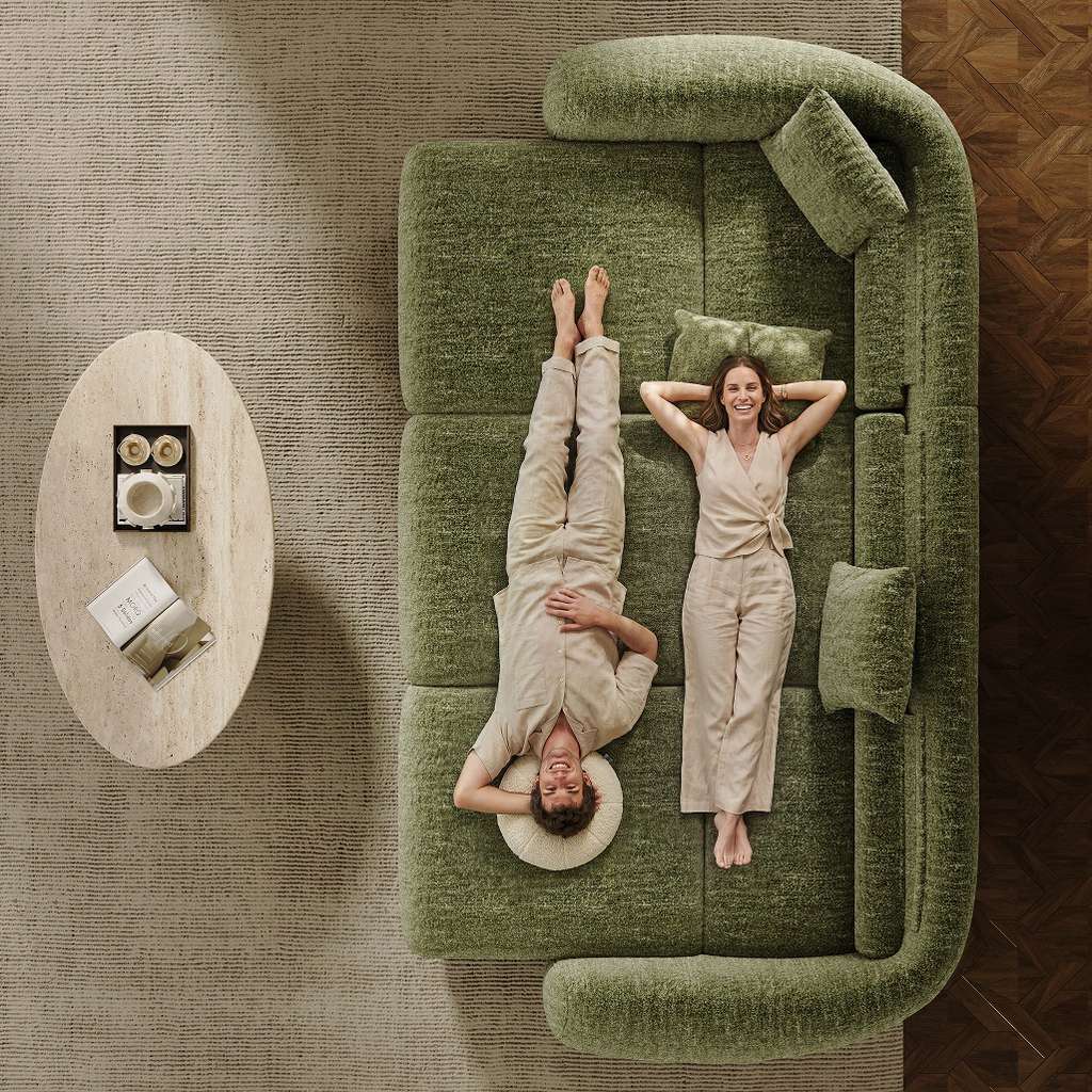 Couple relaxing together on a large green sofa bed in a modern living room.