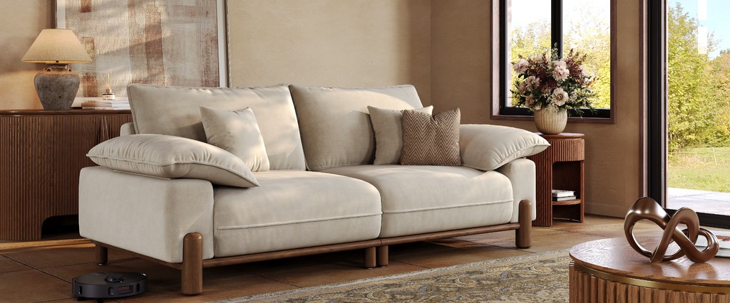 Modern Mediterranean living room with a cream sofa, warm wood furniture, terracotta-toned walls, textured rug, and soft natural light.