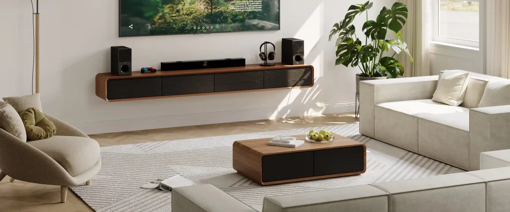 Wall-mounted TV above a floating media console with speakers and a soundbar in a bright modern living room.