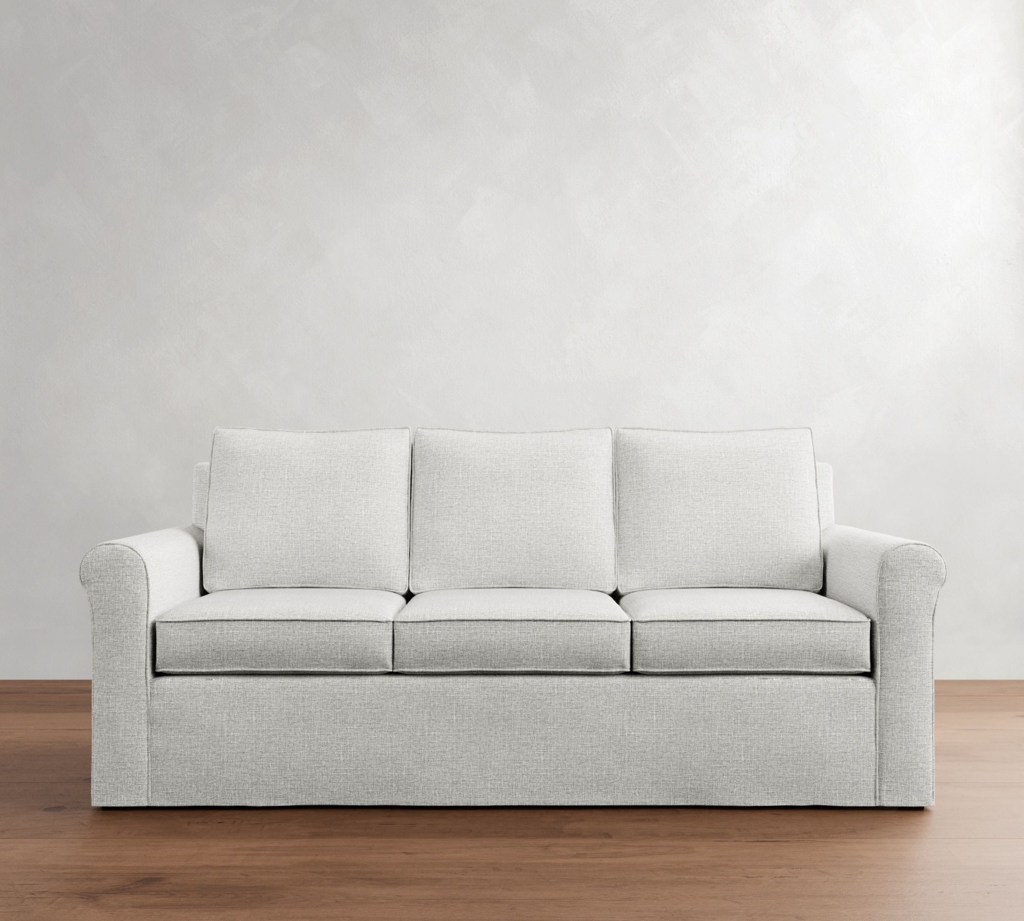 Light gray fabric sofa bed with deep cushions and rounded arms placed against a neutral wall in a modern living room setting.