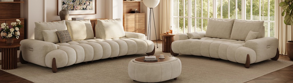 Two cream sofas with rounded cushions facing a matching ottoman coffee table in a bright modern living room.