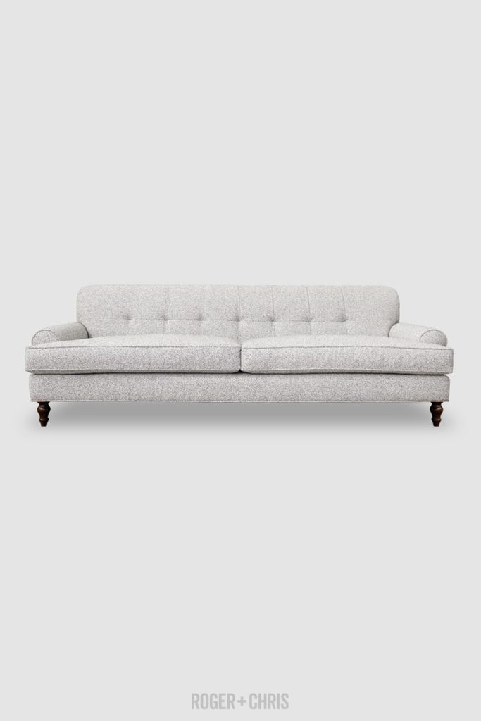 Light gray low-arm sofa with tufted back cushions, curved arms, and dark turned wood legs.