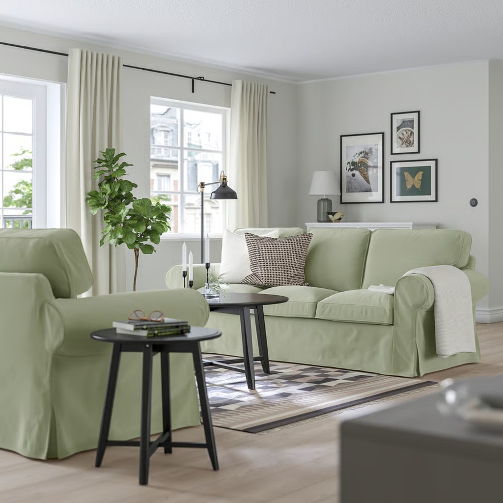 Light green high-arm sofa with matching armchair in a bright living room with large windows and neutral decor.