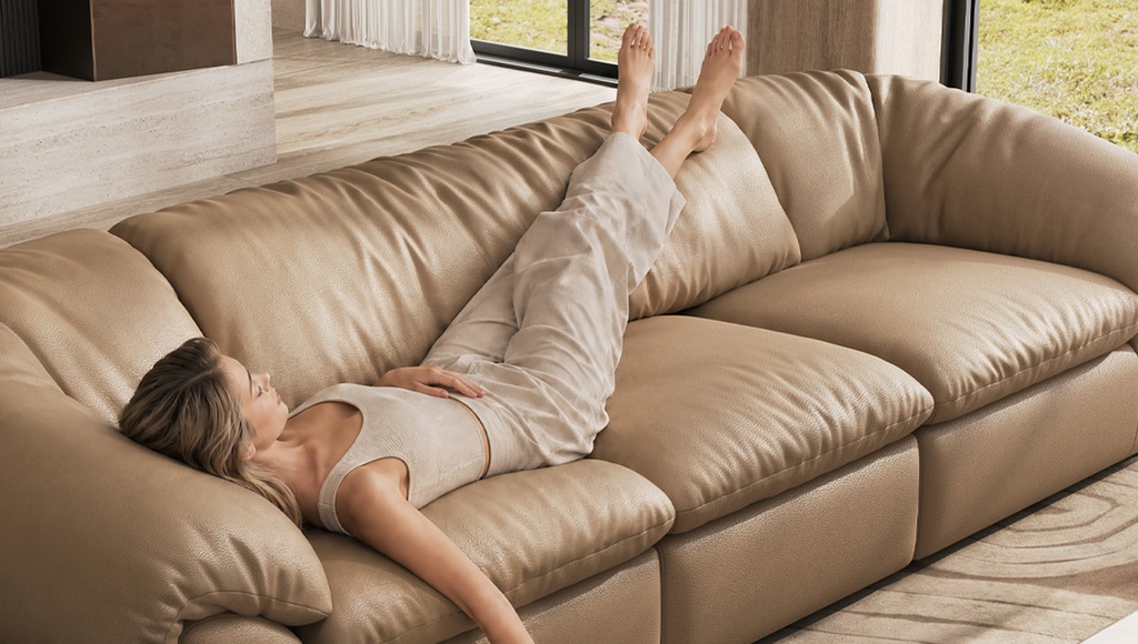 Woman reclining across a beige sectional sofa in a bright modern living room.