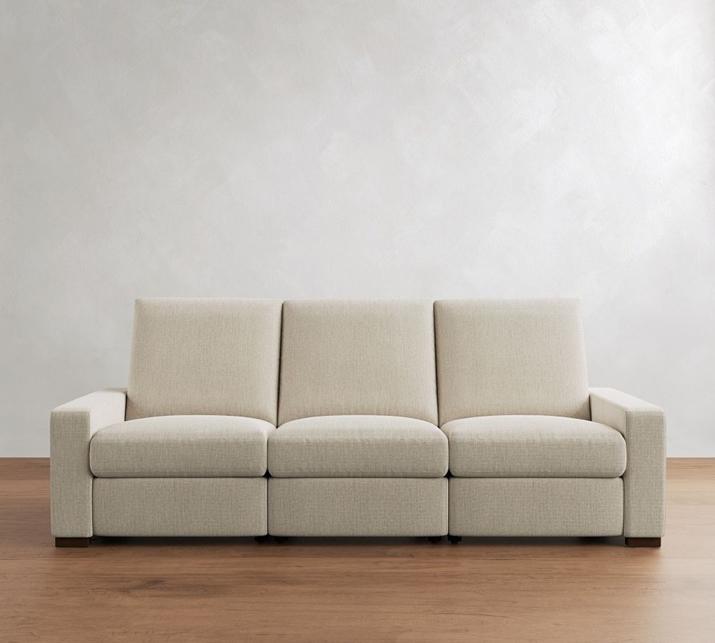 White three-seat reclining sofa with high back cushions and square arms on a light wood floor