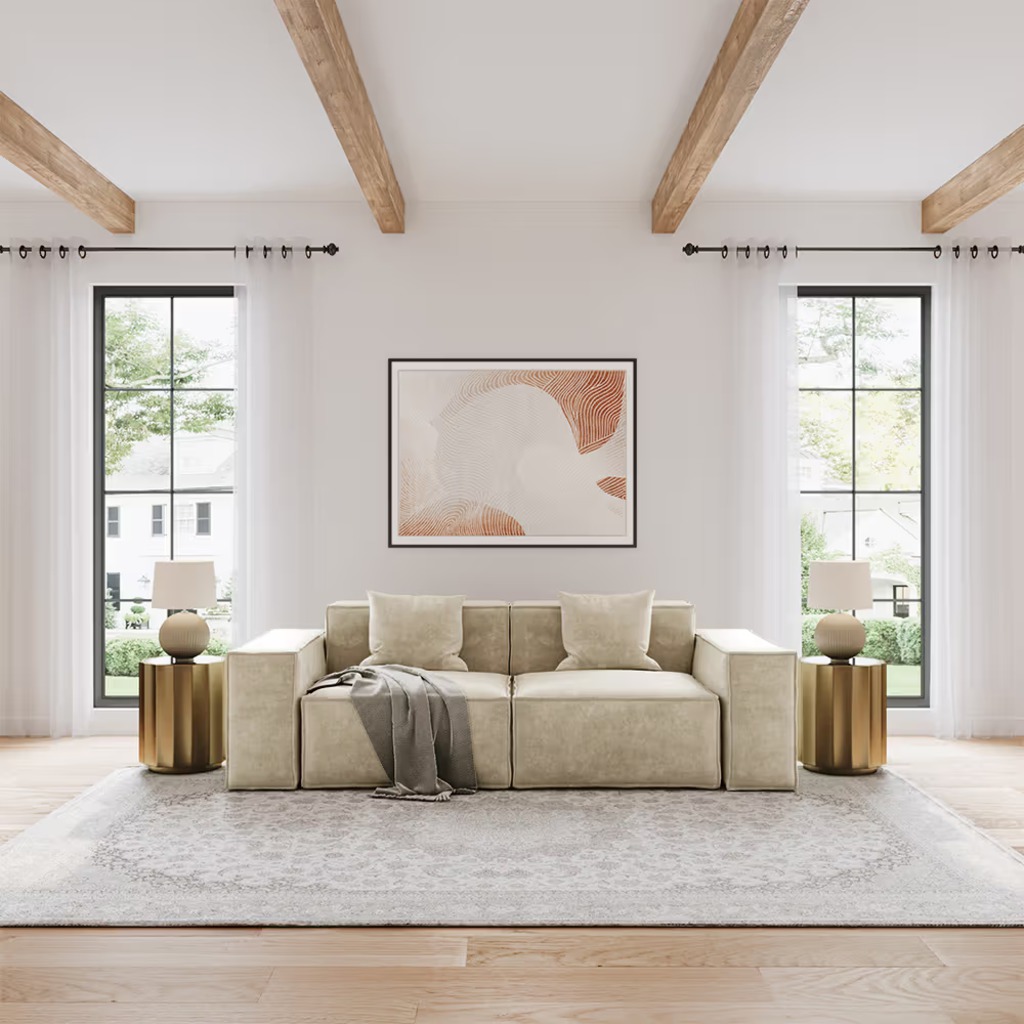 Beige low-arm sofa with broad square arms in a bright modern living room with tall windows and wood ceiling beams.