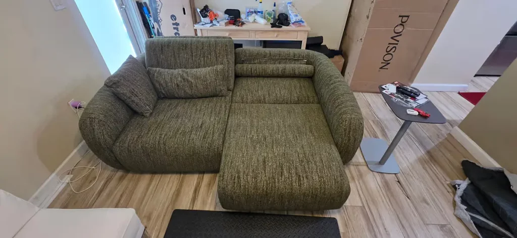 Green power sofa bed extended in a compact apartment living room.