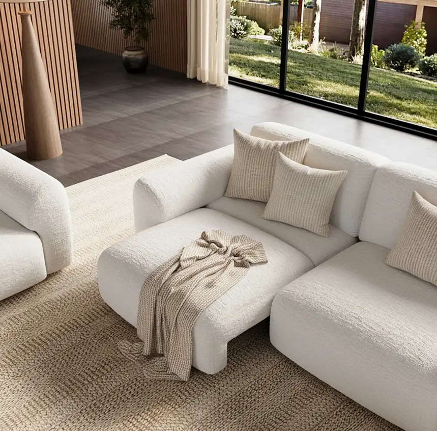 1. White upholstered sofa bed with a chaise in a modern living room with neutral pillows, a knit throw, and large windows.