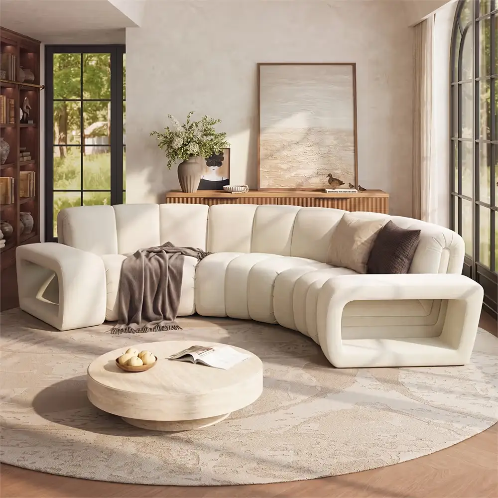 Bright living room with a sculptural curved cream sofa, round coffee table, and softly rounded furnishings.