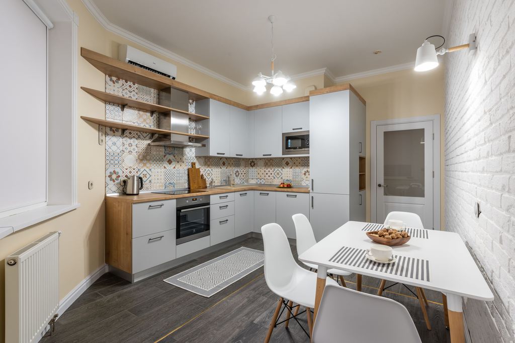 White rectangular dining table placed close to a brick wall in a compact kitchen dining area.