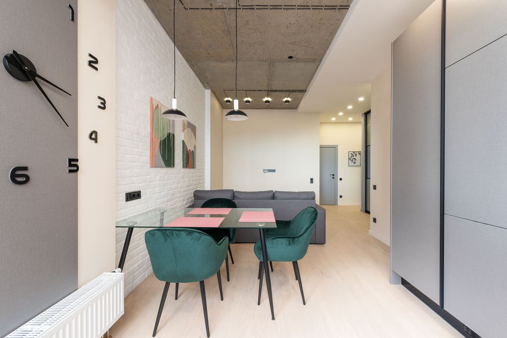 Glass dining table placed close to a white brick wall in a modern open-plan apartment.