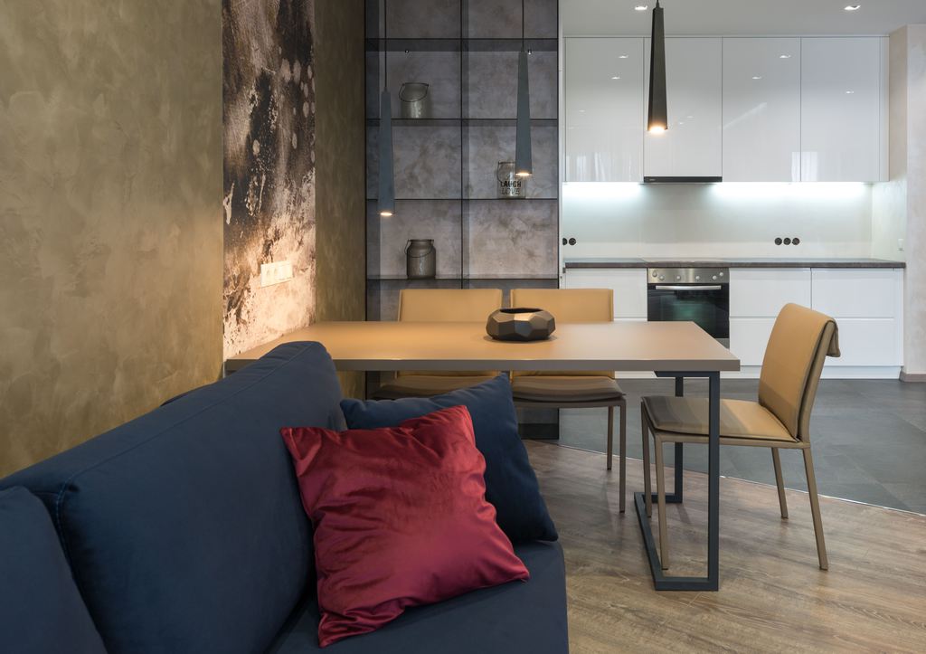 Rectangular dining table placed beside a wall in a modern open-plan kitchen and living room.
