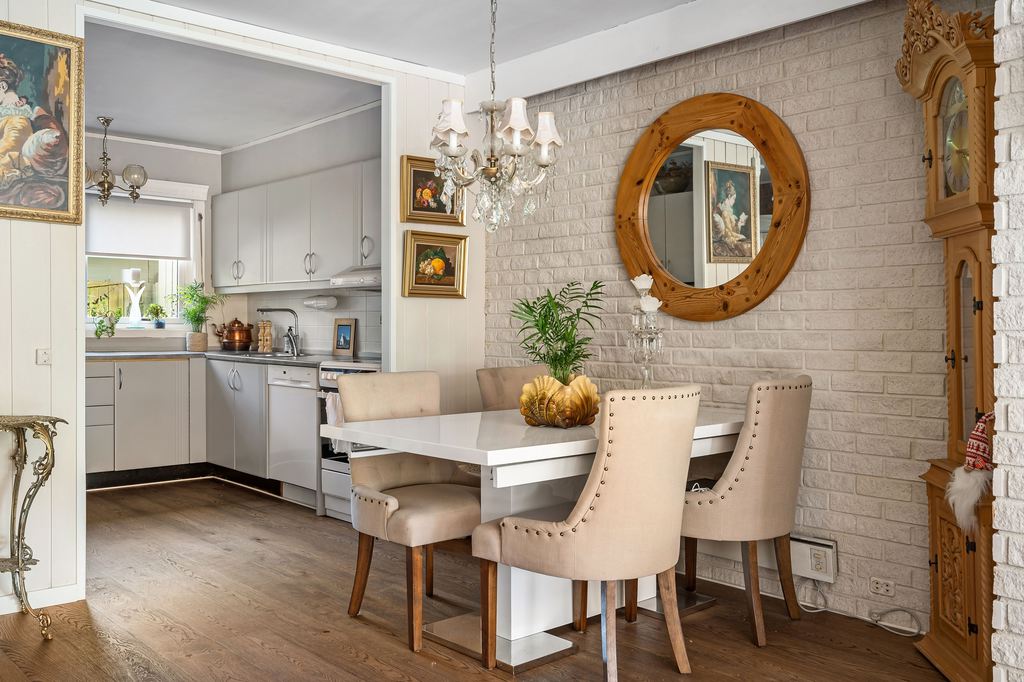 Rectangular dining table placed close to a brick wall beside a compact kitchen.