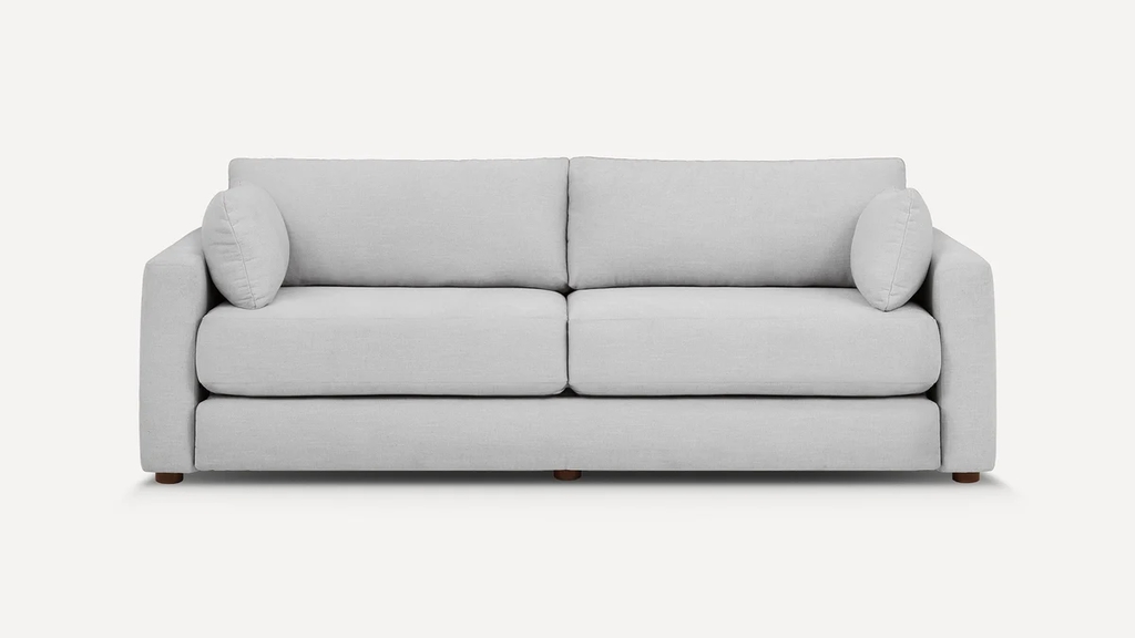 Light gray upholstered sofa bed with two seat cushions, two back cushions, and round side pillows on a white background.