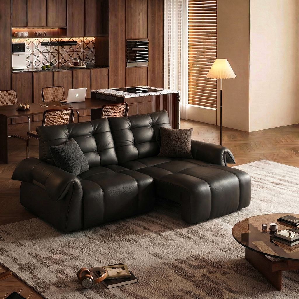 Black leather sofa bed in a home office and living space with a desk and laptop in the background.