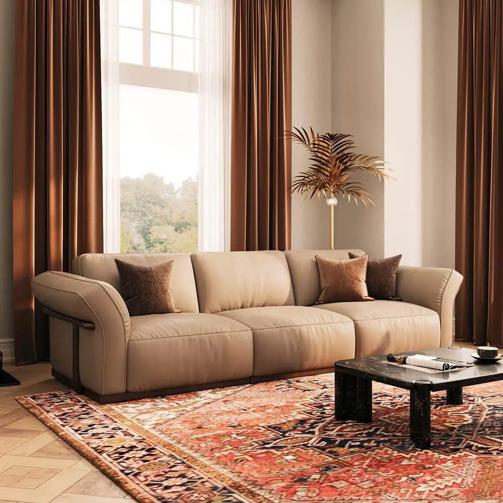 Beige leather sofa with brown throw pillows in an elegant living room featuring floor-length curtains, a black coffee table, and a red patterned rug.
