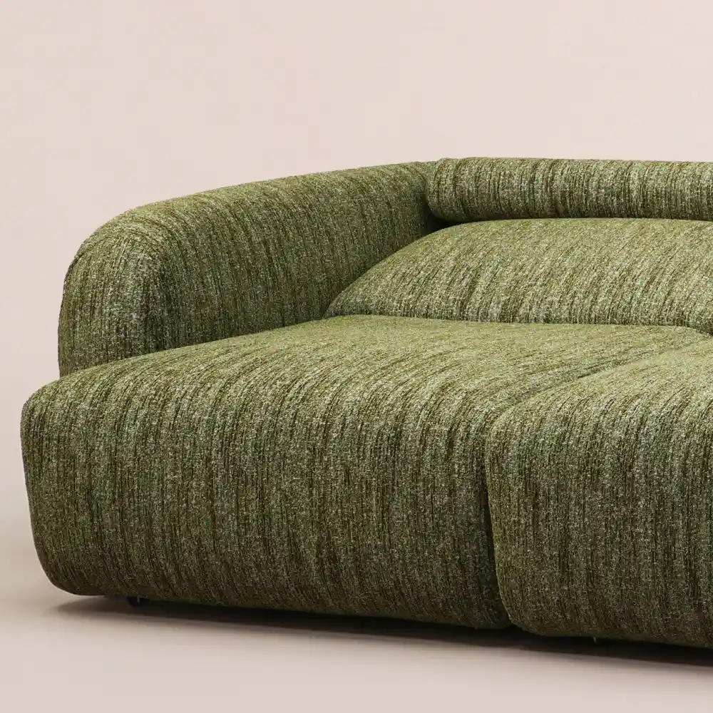 Close-up of a green textured fabric sofa bed with rounded arms, a curved backrest, and deep, cushioned seating.