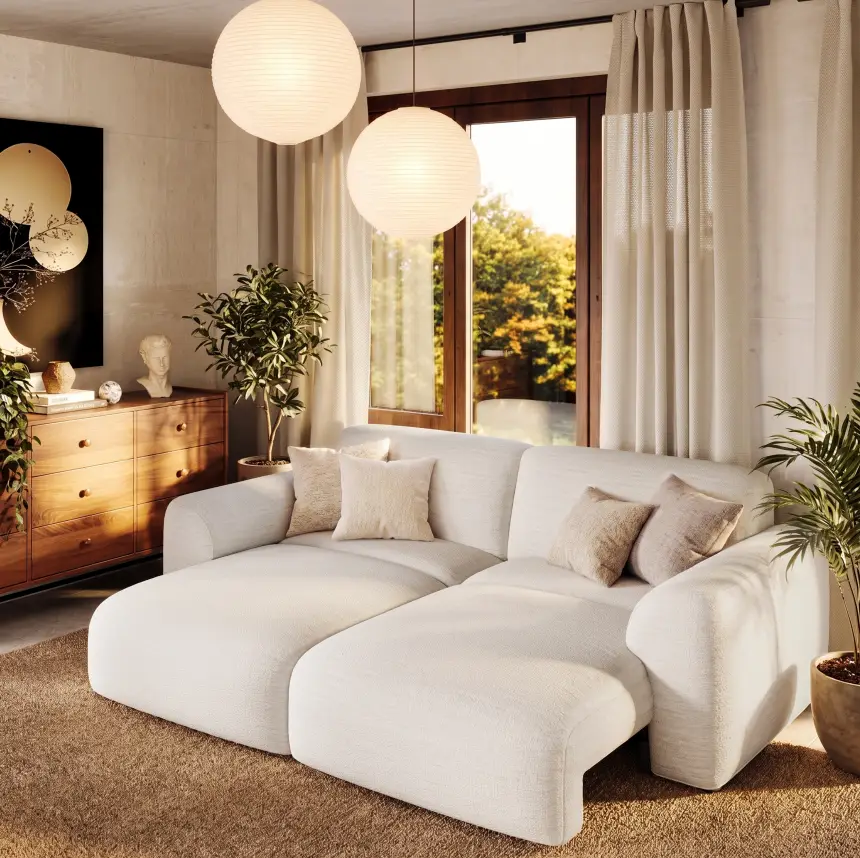 White couch bed with two extended seats, rounded arms, and beige throw pillows in a sunlit living room with wooden furniture and pendant lights.
