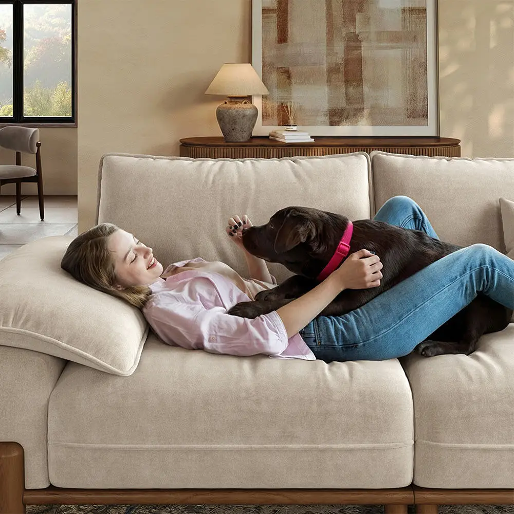 Woman reclining on a beige sofa with a large brown dog resting on her lap in a modern living room.