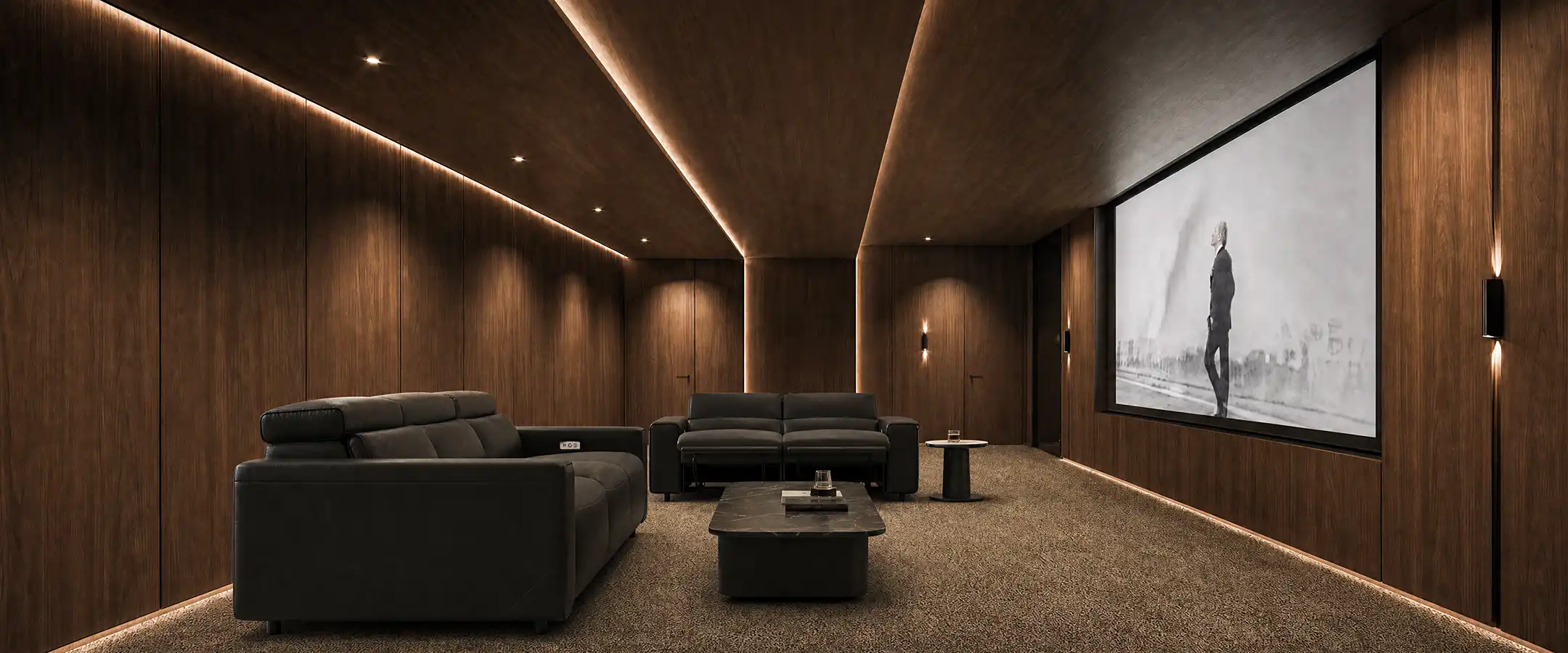 Dark reclining sofas arranged in a home theater with a large projection screen, wood-paneled walls, and warm lighting.