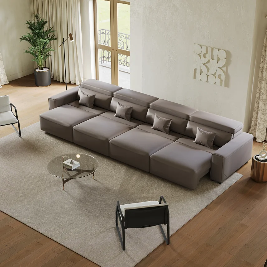 Modern gray sofa bed with extended seats, adjustable headrests, and matching pillows in a bright living room.