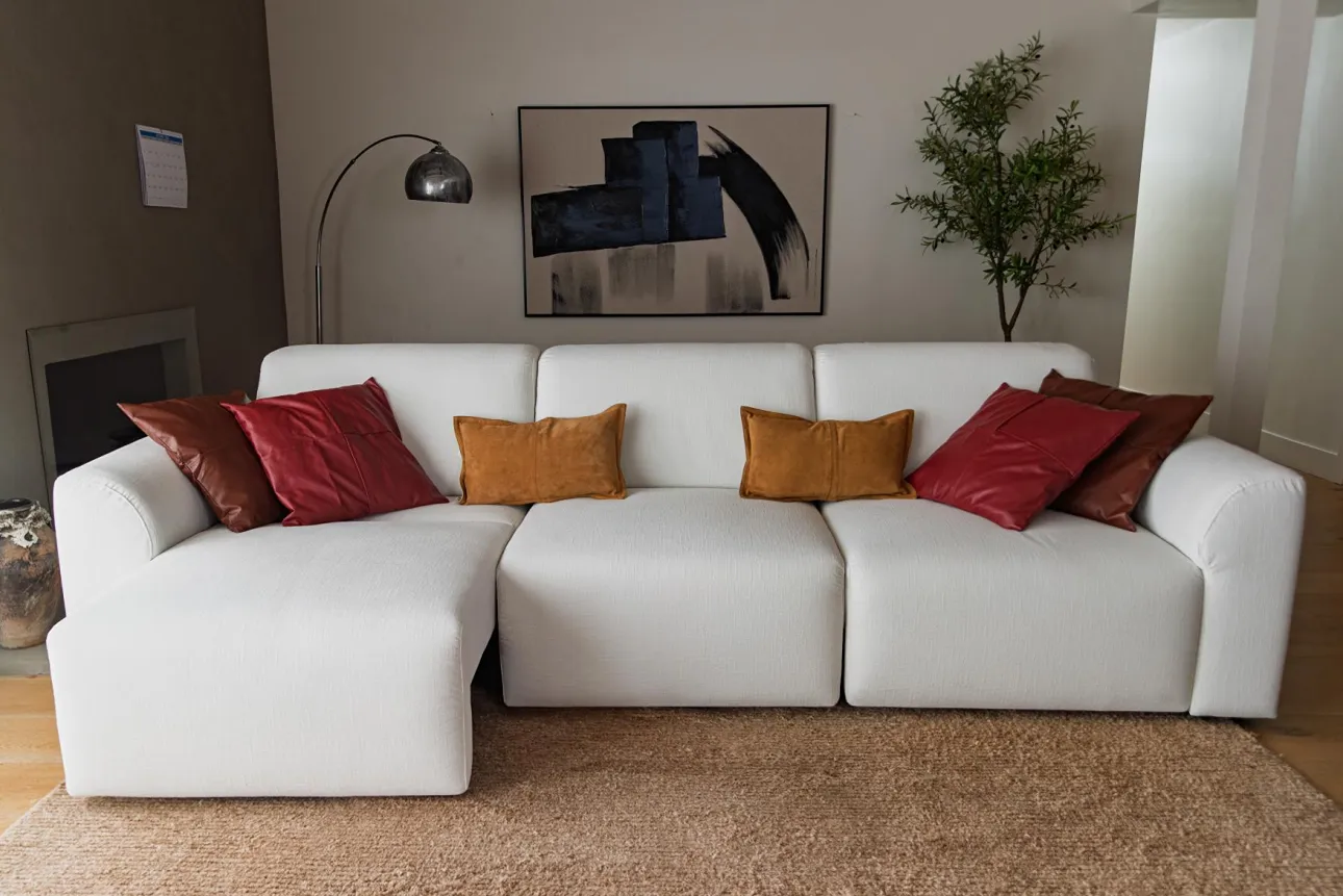 White sleeper sofa with three seat cushions and colorful throw pillows in a modern living room.