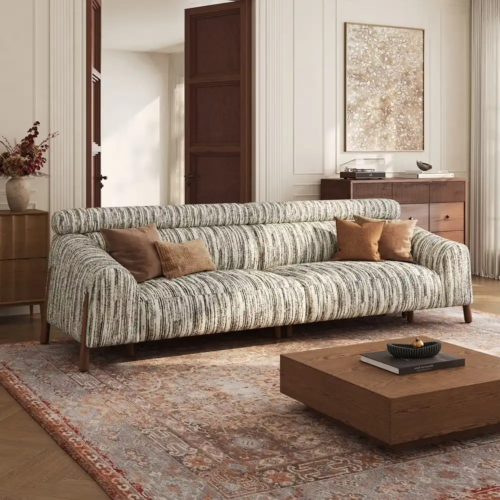 Striped fabric sofa with a curved backrest and wooden legs in a warm, traditional living room.