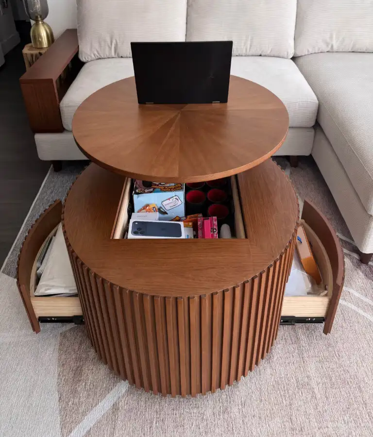 Walnut round lift-top coffee table with raised tabletop, open side drawers, and hidden storage in front of a white sectional sofa.