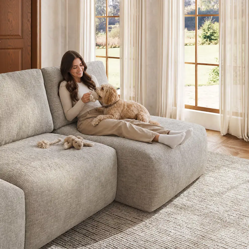 Woman relaxing with a dog on a gray chaise sectional sofa