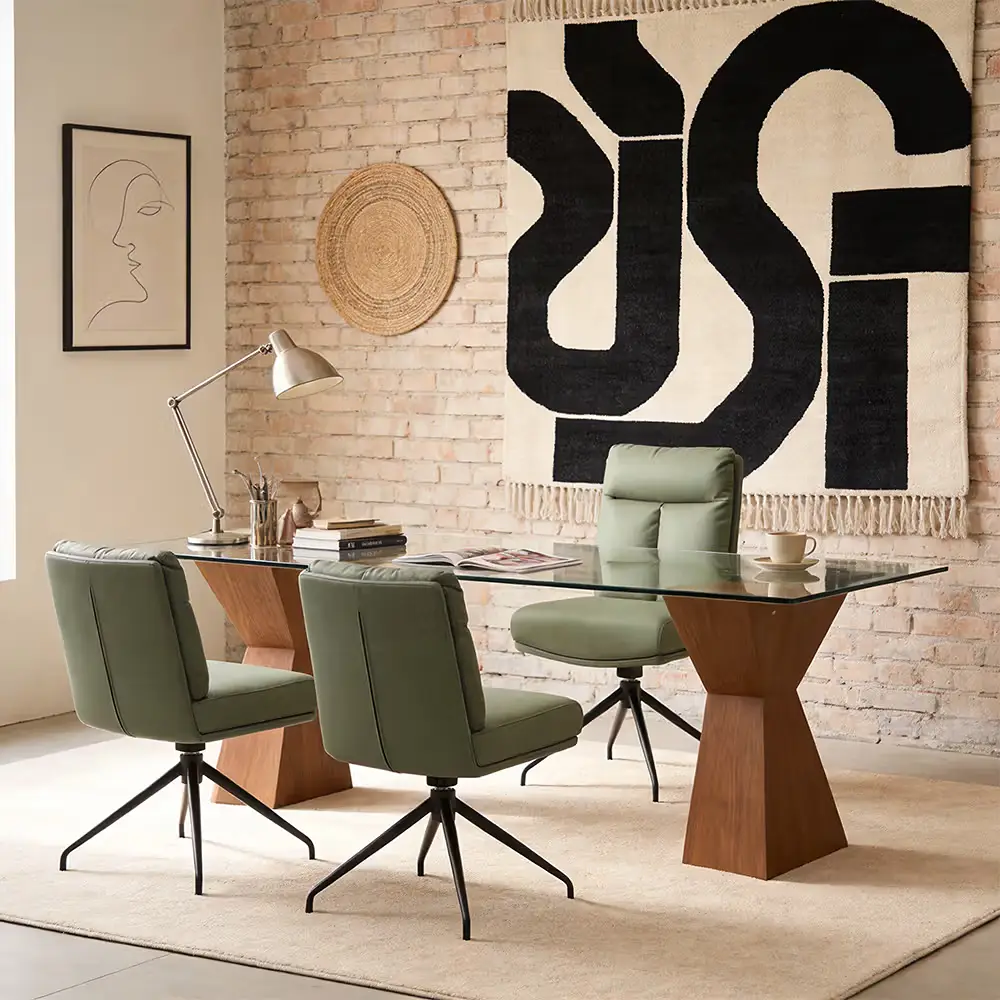 Modern home office with a glass-top desk, three green upholstered chairs, and contemporary wall decor.